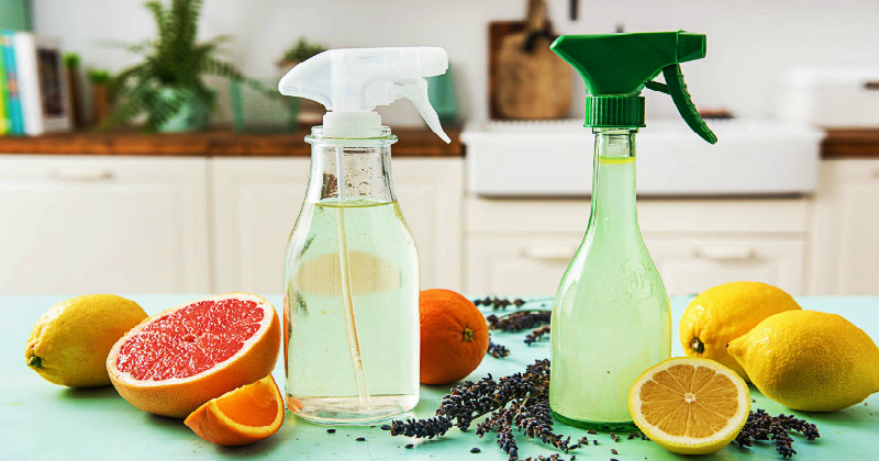 two spray bottles kept on a table with lemon and rosemary