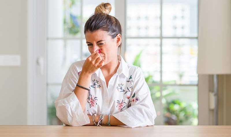 a beautiful young woman sitting inside her house and covering her nose with her hand