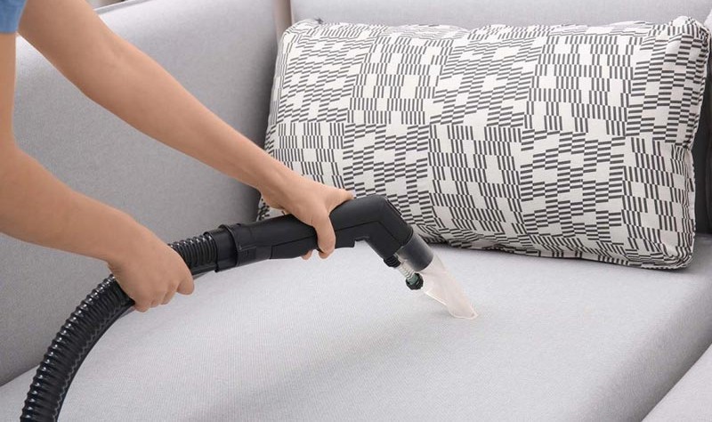 cropped image of a woman vacuuming a couch