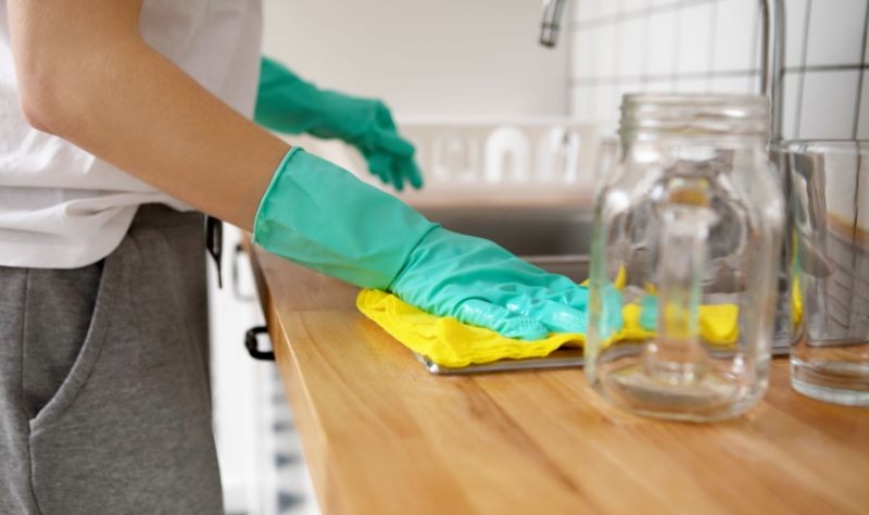 cropped image of a woman wiping kitchen countertop