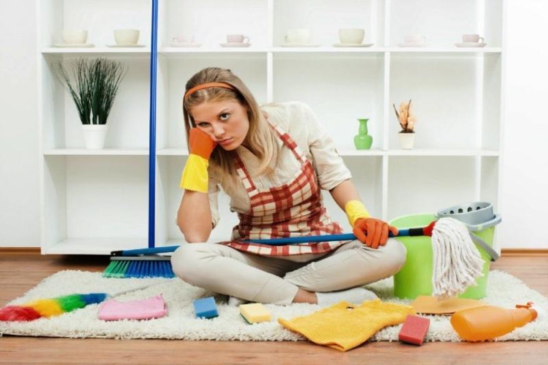 angry young woman sitting on the floor with some wiping cloths and spray bottles