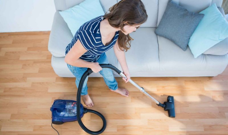 Young woman vacuuming the floor