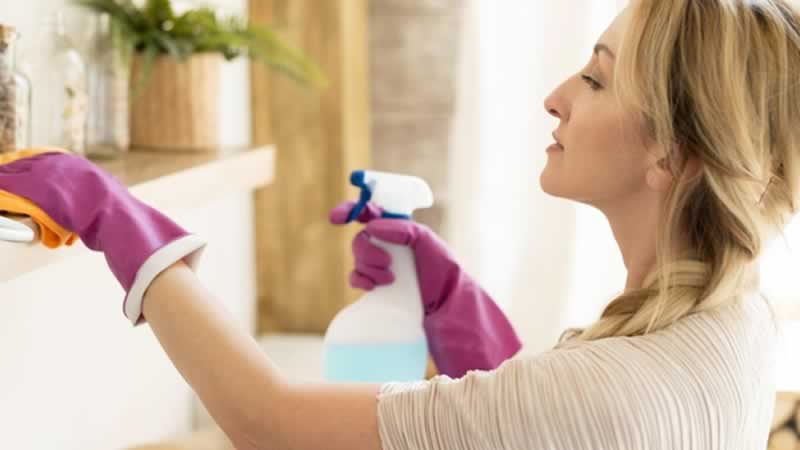 young woman disinfecting a surface with a spray