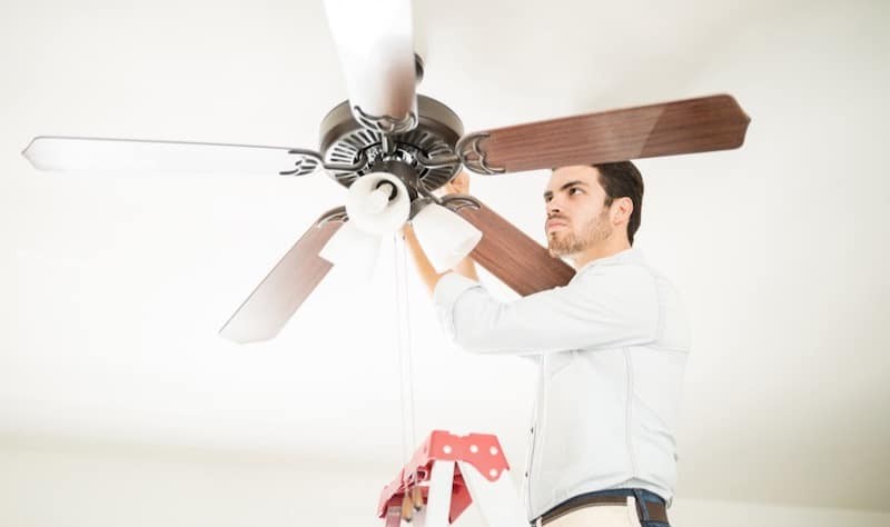 young man trying to fix a ceiling fan