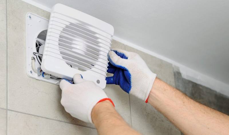 Men hands in white gloves holding bathroom exhaust fan