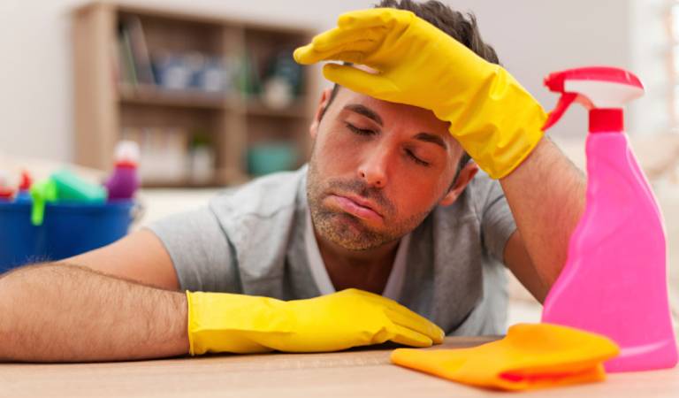 Man in yellow gloves seeing upset with pink bottle and orange cloth