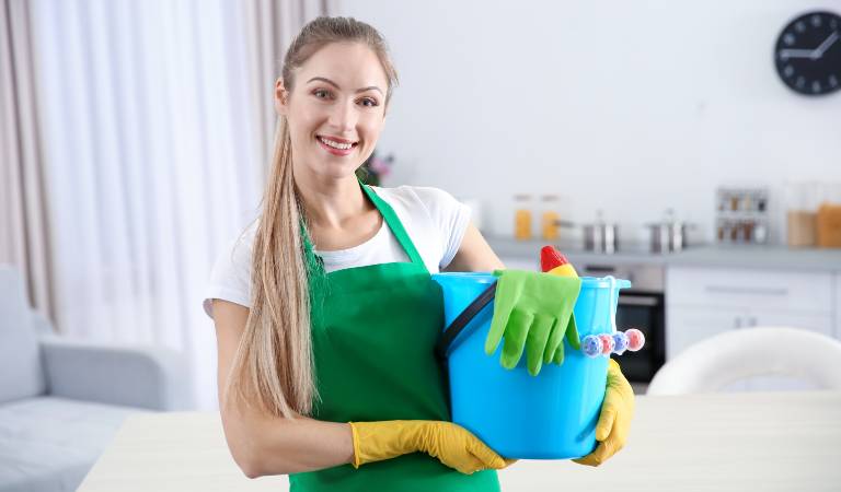 Woman in white green dress holding a blue basket filled with tools and supplies