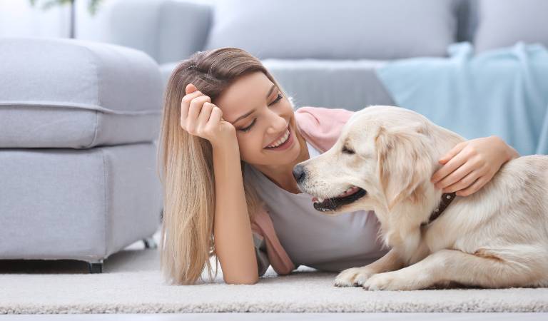 Woman is playing with her dog inside a room