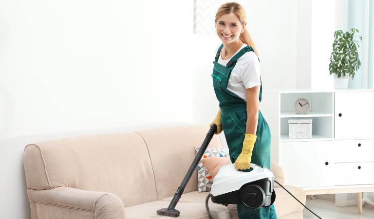 Woman in white green dress holding a vacuum cleaner in her hand and smiling