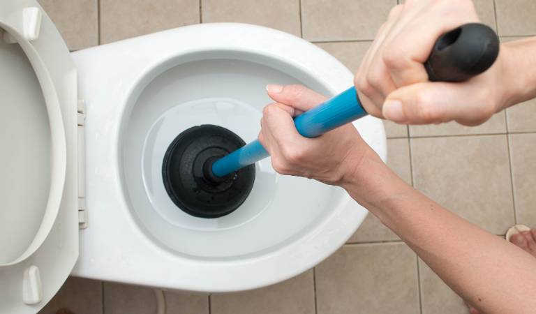 Man cleaning toilet bowl using cleaning stick.