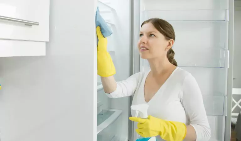 young woman cleaning up a refrigerator