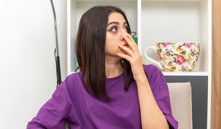 woman sitting on a couch and looking concerned about the household odour