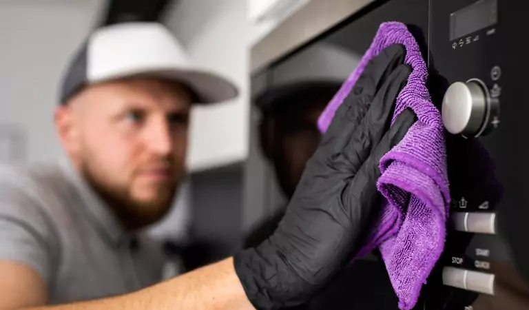young man wiping an oven with a cloth