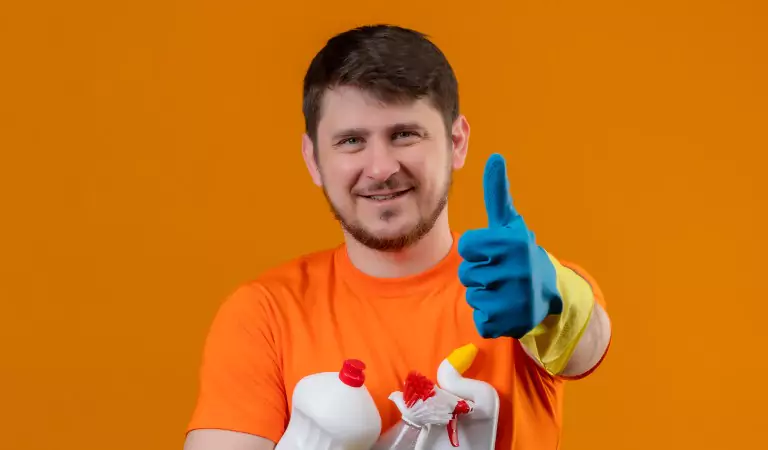 young man showing thumbs up and holding some cleaning supplies
