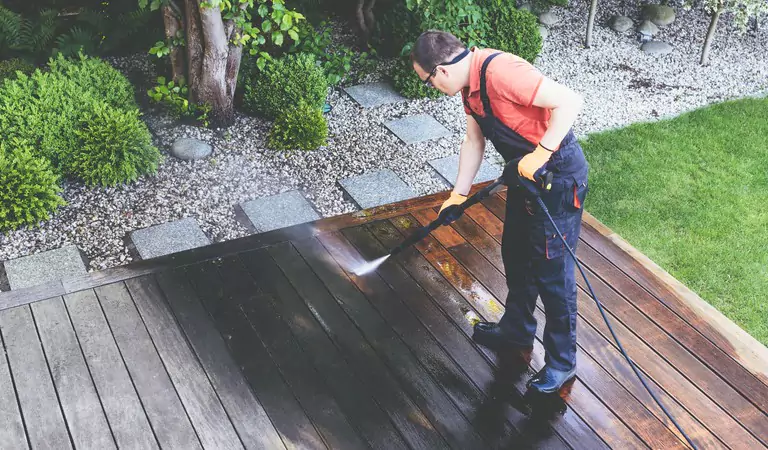young man pressure cleaning the outdoor of a house