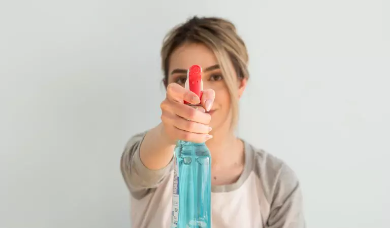 woman holding a cleaning spray bottle and ready to clean