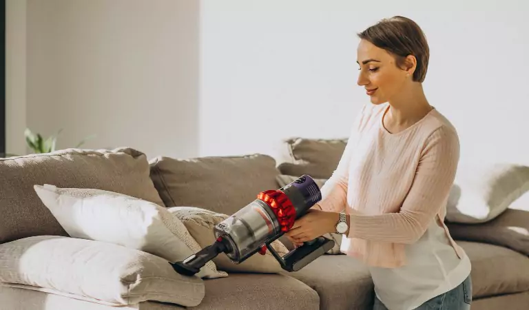 young woman vacuuming a sofa