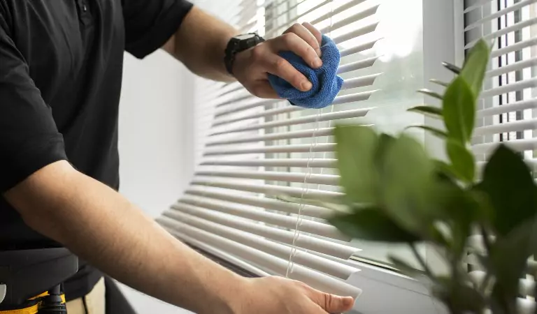 cropped picture of a person cleaning window blinds