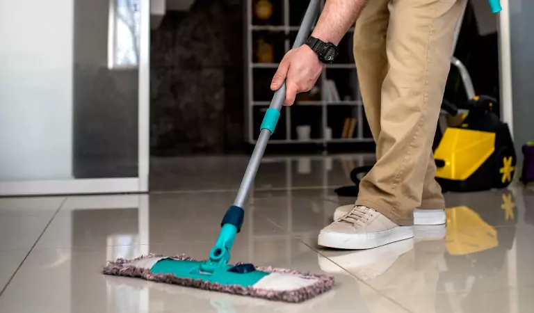 person wiping a floor surface with a wiper
