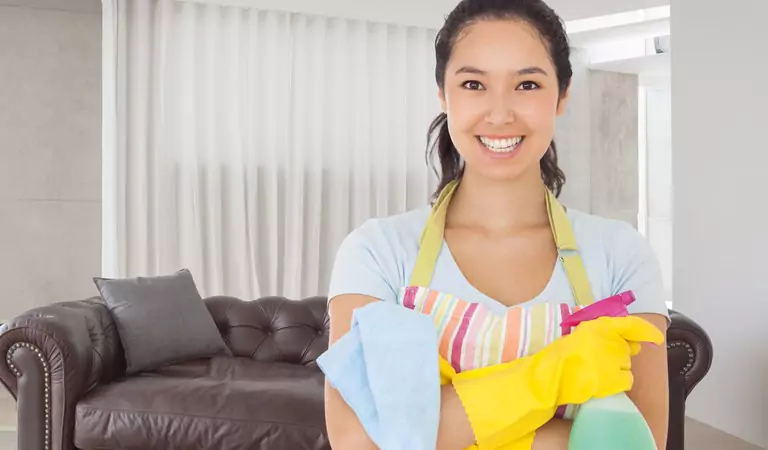 woman with some cleaning supplies and a leather couch at the back