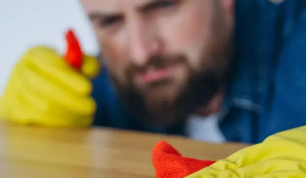 woman cleaning wooden surface with a cleaning spray