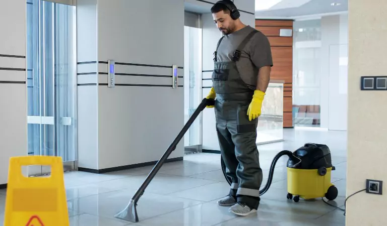 young man cleaning the floor with a vacuum cleaner