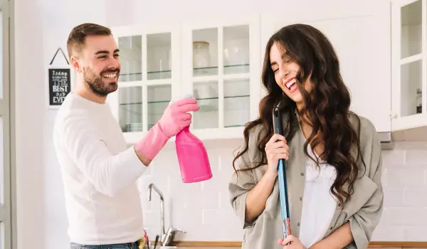 couple enjoying while cleaning their house
