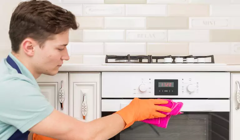 young man cleaning an oven