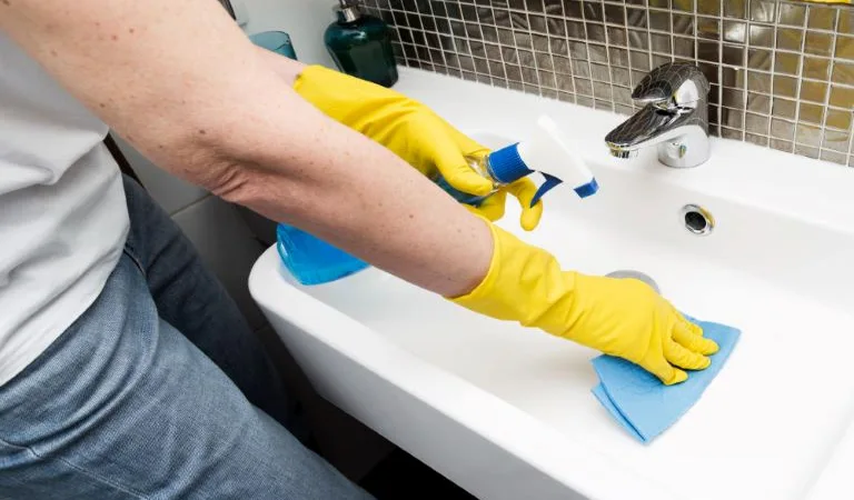 Woman with rubber gloves cleaning the sink