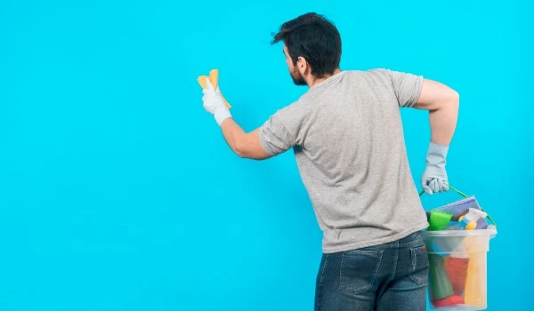 Concept of man cleaning his home with copyspace on wall