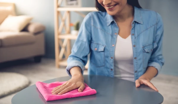 young woman using microfibre cloth to clean the table