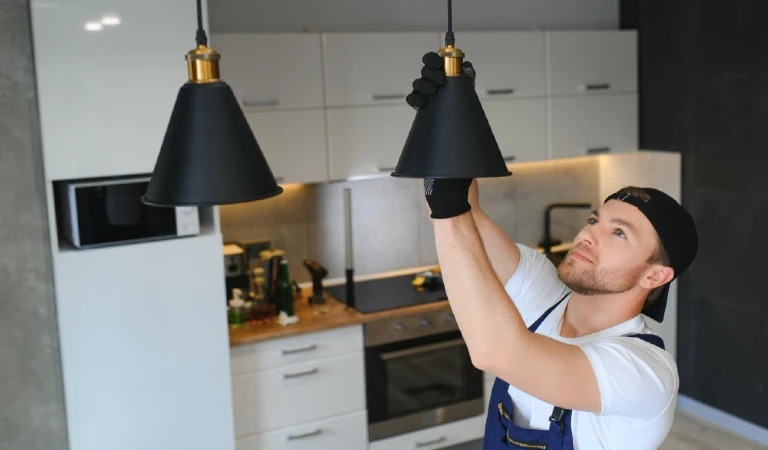A male cleaning light bulbs in the ceiling