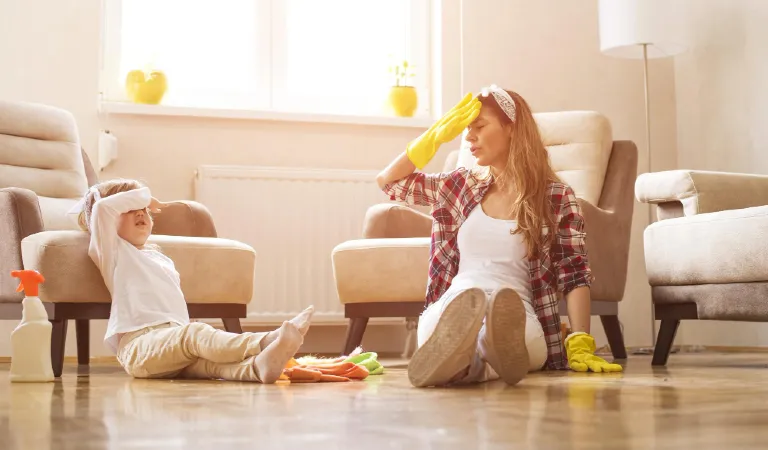 Mother and a daughter feeling exhausted after cleaning home together