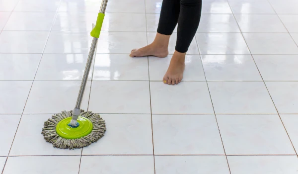 Women using mop cleaning dirty floor tiles in the house
