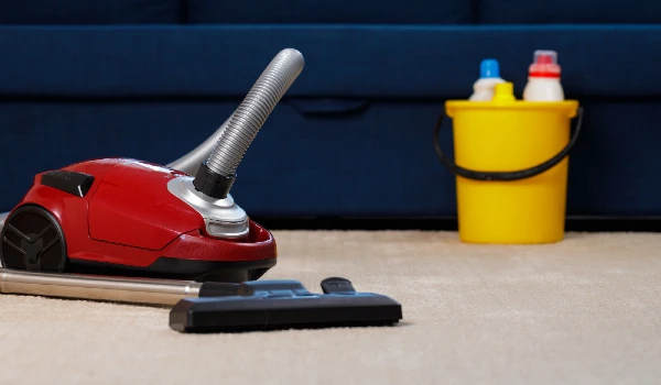 Red vacuum cleaner on a beige carpet