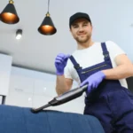 Housekeeper holding modern washing vacuum cleaner and cleaning dirty sofa with stain with professionally detergent professional springclean at home concept