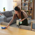 Woman with bottle in home for housekeeping hygiene and wooden furniture maintenance on weekend surface