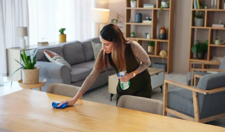 Woman with bottle in home for housekeeping hygiene and wooden furniture maintenance on weekend surface