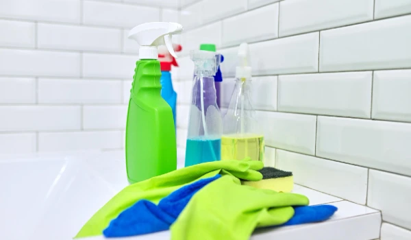 Cleaning in bathroom, hygiene, cleanliness in house. Detergents rag gloves on the background of white tiled wall