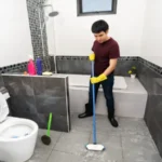 Young man using brush to cleaning the tile in the bathroom