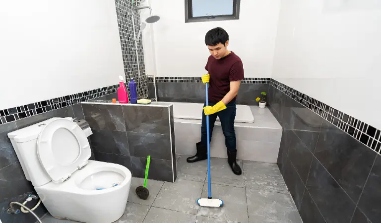 Young man using brush to cleaning the tile in the bathroom